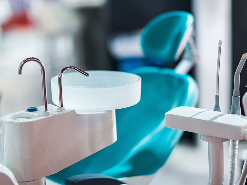 A modern dental practice with a blue chair, dental equipment, and a clean, sterile environment.